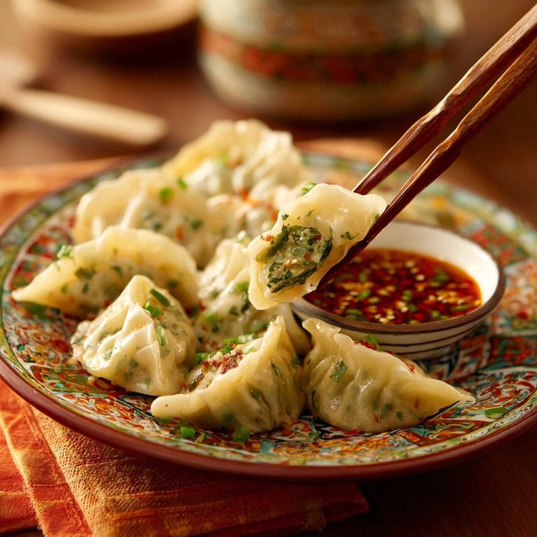 Gedämpfte Gemüse-Dumplings mit Chili-Dip in Nahaufnahme, von Essstäbchen gehalten, mit einem Stück, das in einen Dip getaucht wird.