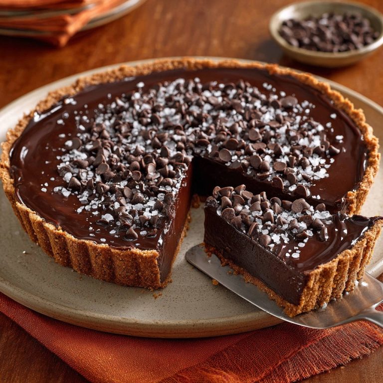 Schoko-Ganache-Tarte mit Meersalz im Anschnitt, mit Blick auf die cremige Füllung und den knusprigen Boden. Ein köstliches Dessert mit Schokoladenstückchen und Meersalzflocken.