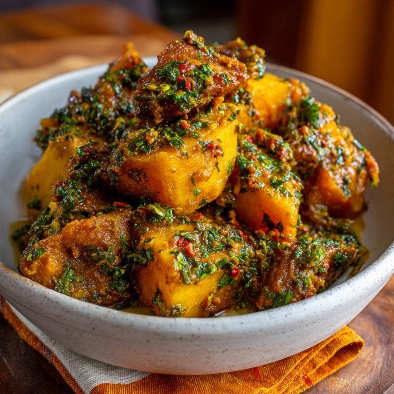 Zarte Yamswürfel mit aromatischer Kräutersauce in einer Schüssel, von oben betrachtet. Die leckeren Yamswürfel sind reichlich mit frischen Kräutern bedeckt.