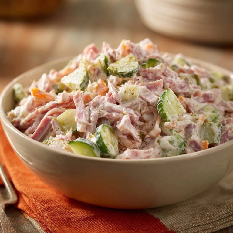 Cremiger Schinken-Gemüse-Salat in Nahaufnahme, angerichtet in einer hellen Schüssel, mit Gurken, Karotten und Gewürzen garniert.