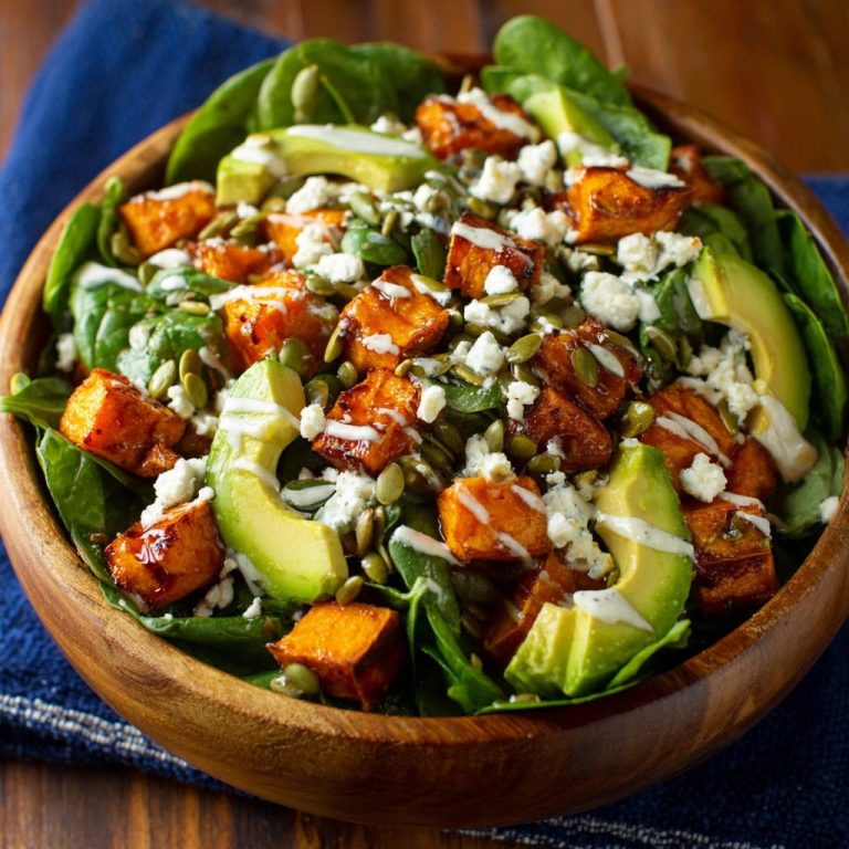 Herbstlicher Süßkartoffel-Avocado-Salat in einer Holzschüssel, garniert mit Avocado und Kürbiskernen, von oben betrachtet. Ein farbenfrohes und gesundes Gericht.