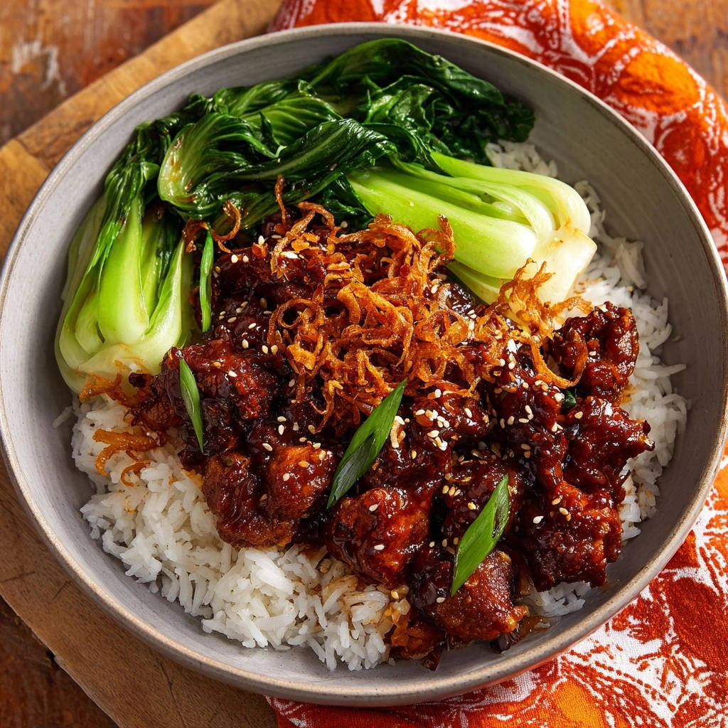 Knuspriges Asia-Hähnchen mit glänzender Glasur in einer Schüssel serviert, garniert mit knusprigen Zwiebeln und Bok Choy.