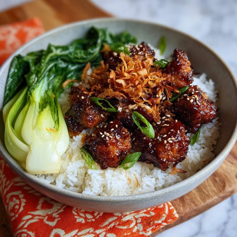 Knuspriges Asia-Hähnchen mit glänzender Glasur serviert in einer Schüssel mit Reis, Bok Choy und knusprigen Zwiebeln, garniert mit Sesam.