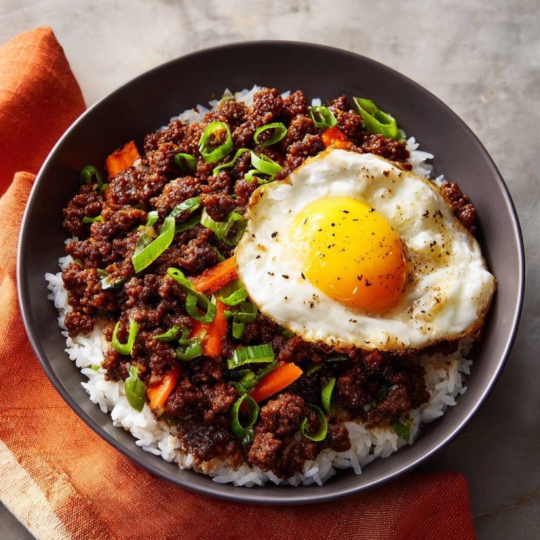 Würzige Hackfleisch-Bowl mit Spiegelei in einer Schüssel, von oben gesehen. Saftiges Hackfleisch mit Spiegelei und frischen Kräutern serviert.