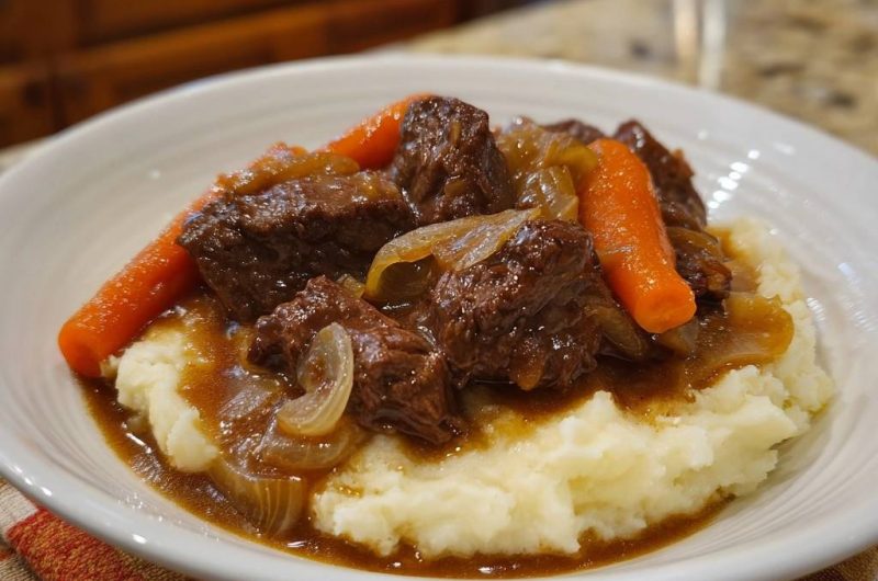 Butterzartes Rindergulasch mit Karotten und Zwiebeln auf cremigem Püree