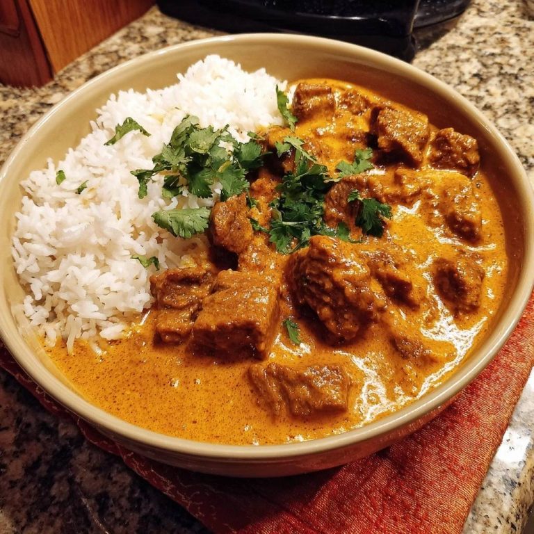 Saftiges Rindfleisch-Curry mit Reis, garniert mit frischem Koriander, serviert in einer rustikalen Schüssel auf einem Tisch.
