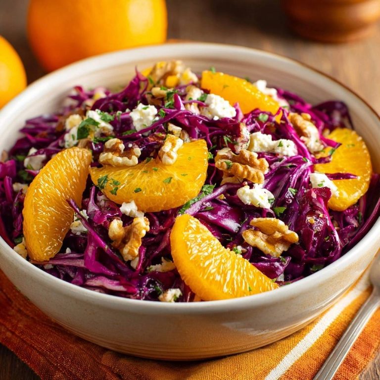 Rotkohl-Orangen-Salat mit Walnüssen & Feta in einer Schüssel, serviert mit frischen Orangen-Spalten und knackigen Walnüssen.