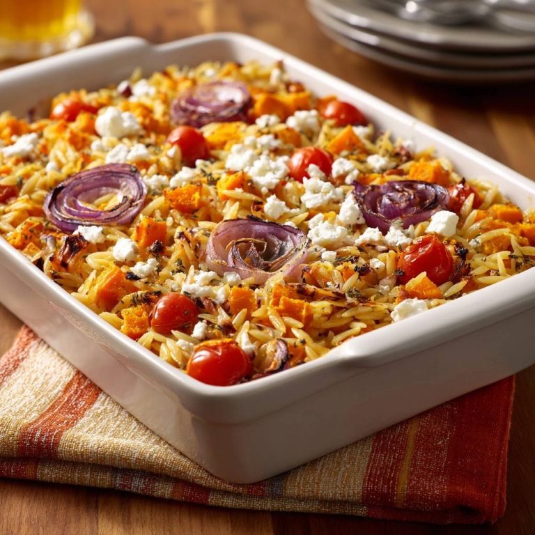Gebackener Kürbis-Orzo mit Tomaten und Feta, eine Nahaufnahme, die die Textur und die Zutaten des Gerichts zeigt.