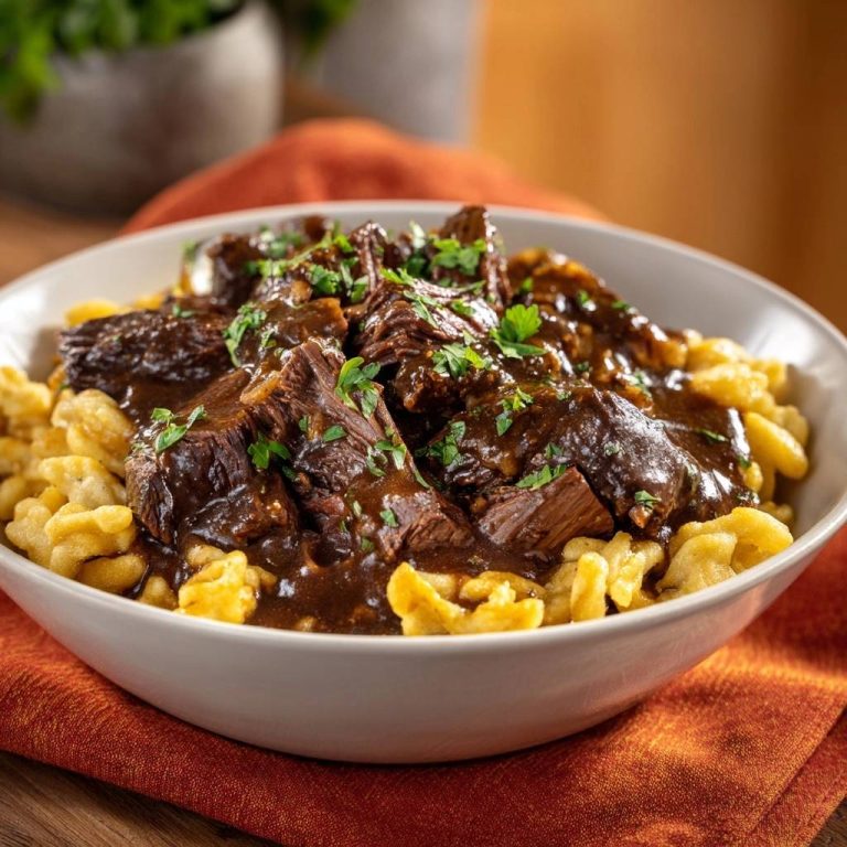 Zartes Rindergulasch mit Spätzle, serviert in einer Schüssel, liebevoll mit frischer Petersilie garniert. Das herzhafte Gericht ist perfekt zubereitet.