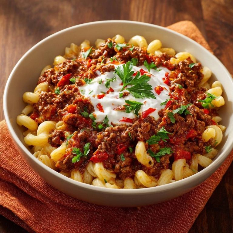 Fusilli mit Hacksoße und Joghurt-Topping in einer Schüssel aus der Vogelperspektive, serviert mit frischen Kräutern und einem cremigen Joghurt-Topping.