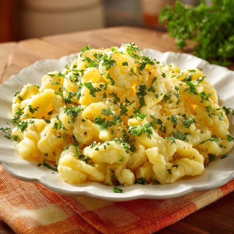 Klassische Butterspätzle, serviert auf einem weißen Teller, mit frischer Petersilie garniert. Ein einfaches und köstliches Gericht für jeden Anlass.