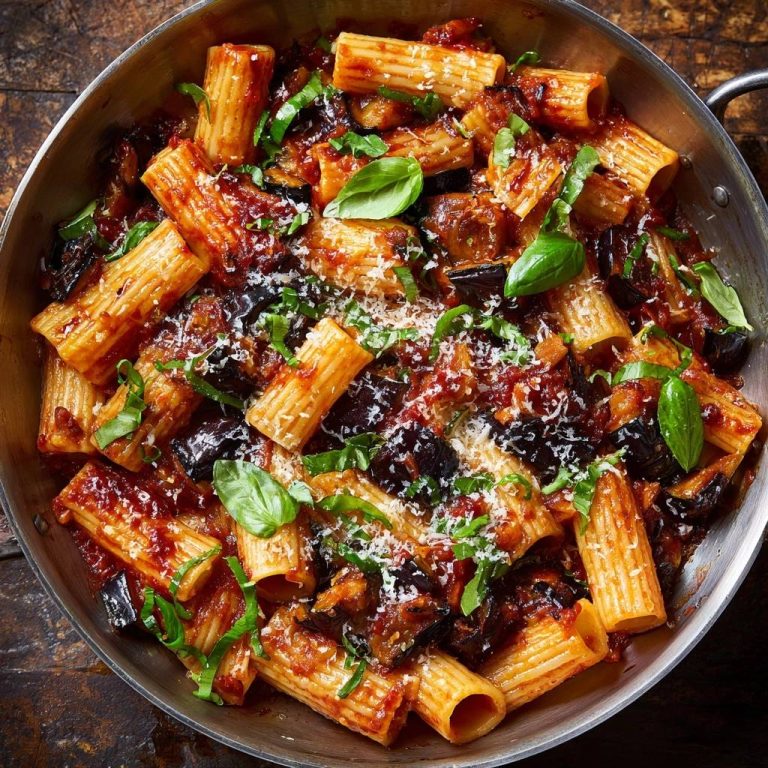 Rigatoni alla Norma, serviert in einer Pfanne, mit Auberginen, Tomatensauce, Basilikum und Parmesan. Ein köstliches italienisches Gericht.