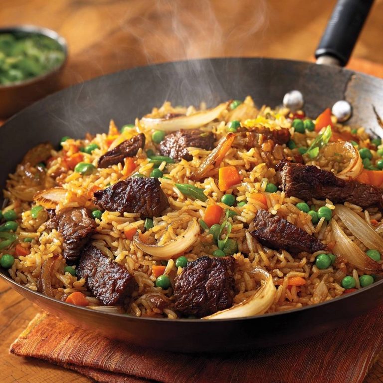 Herzhafte Rindfleisch-Reispfanne dampfend im Wok mit Erbsen, Karotten und Zwiebeln, frisch zubereitet.